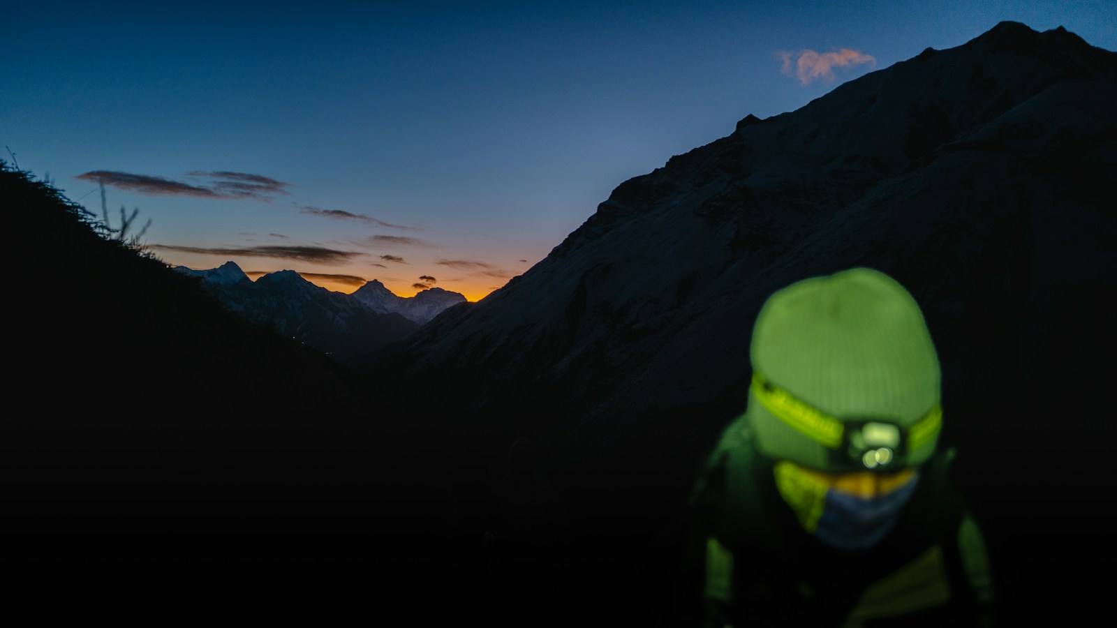 夕暮れの山でヘッドライトを点灯する登山者