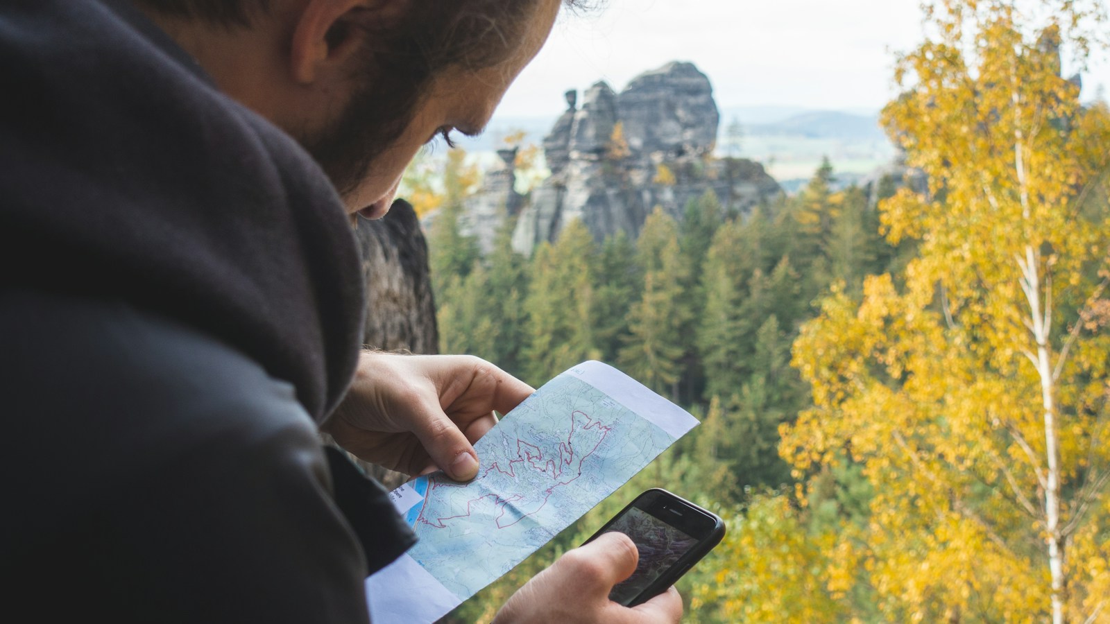 屋外でスマートフォンの地図を確認する登山者